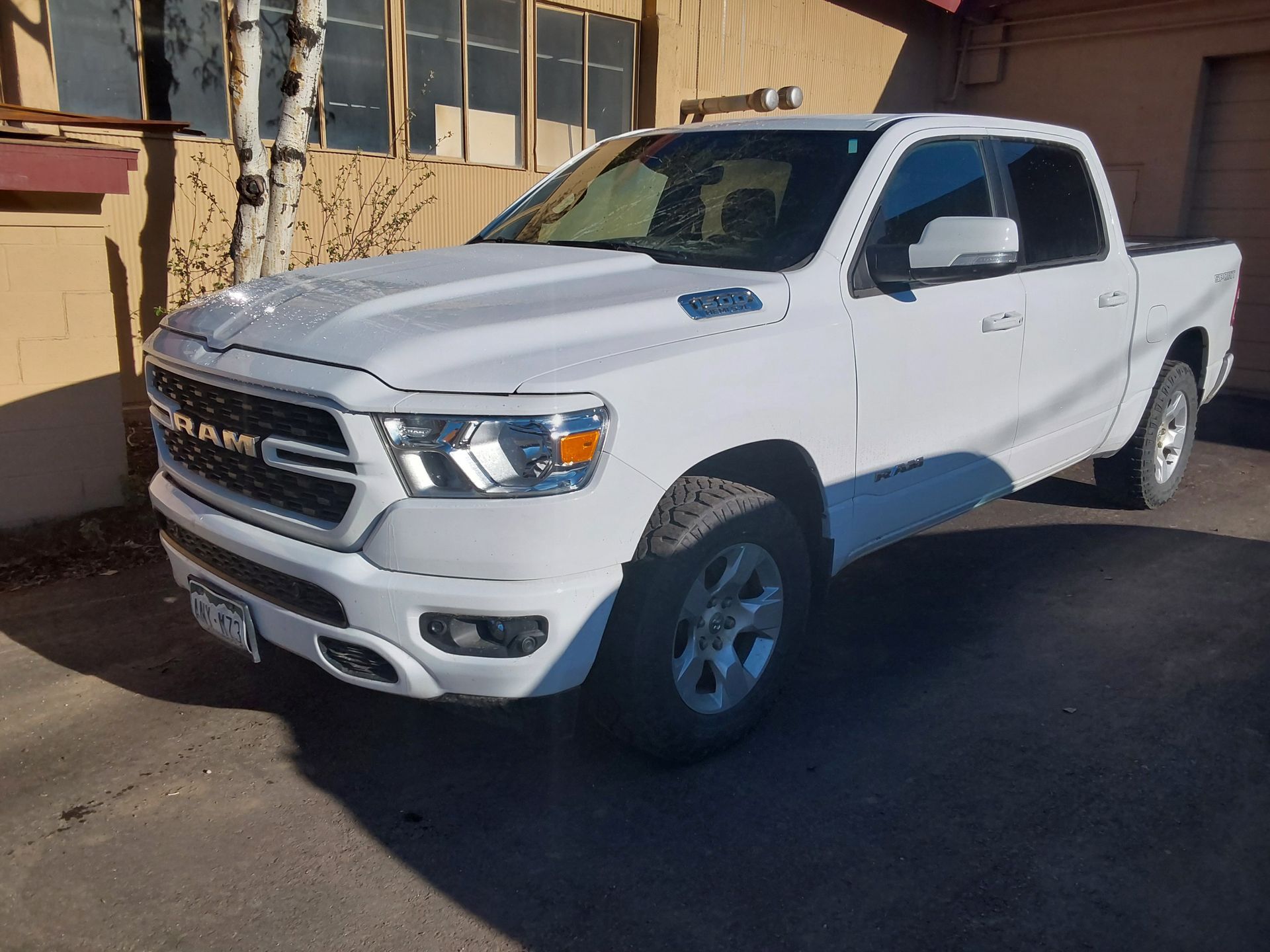 A white ram 1500 truck is parked in front of a building.