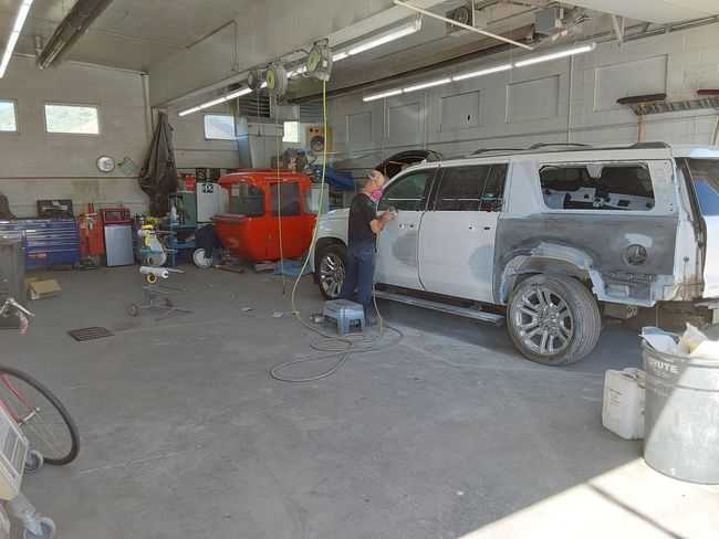 A man is standing next to a white suv in a garage.