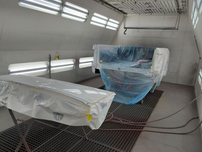 A boat is being painted in a paint booth.