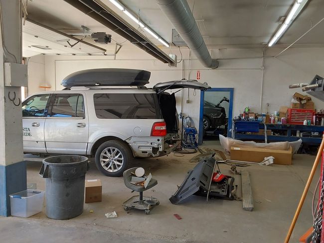 A white suv is parked in a garage with its trunk open.