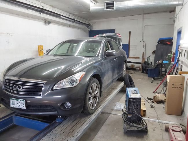 A car is sitting on a ramp in a garage.