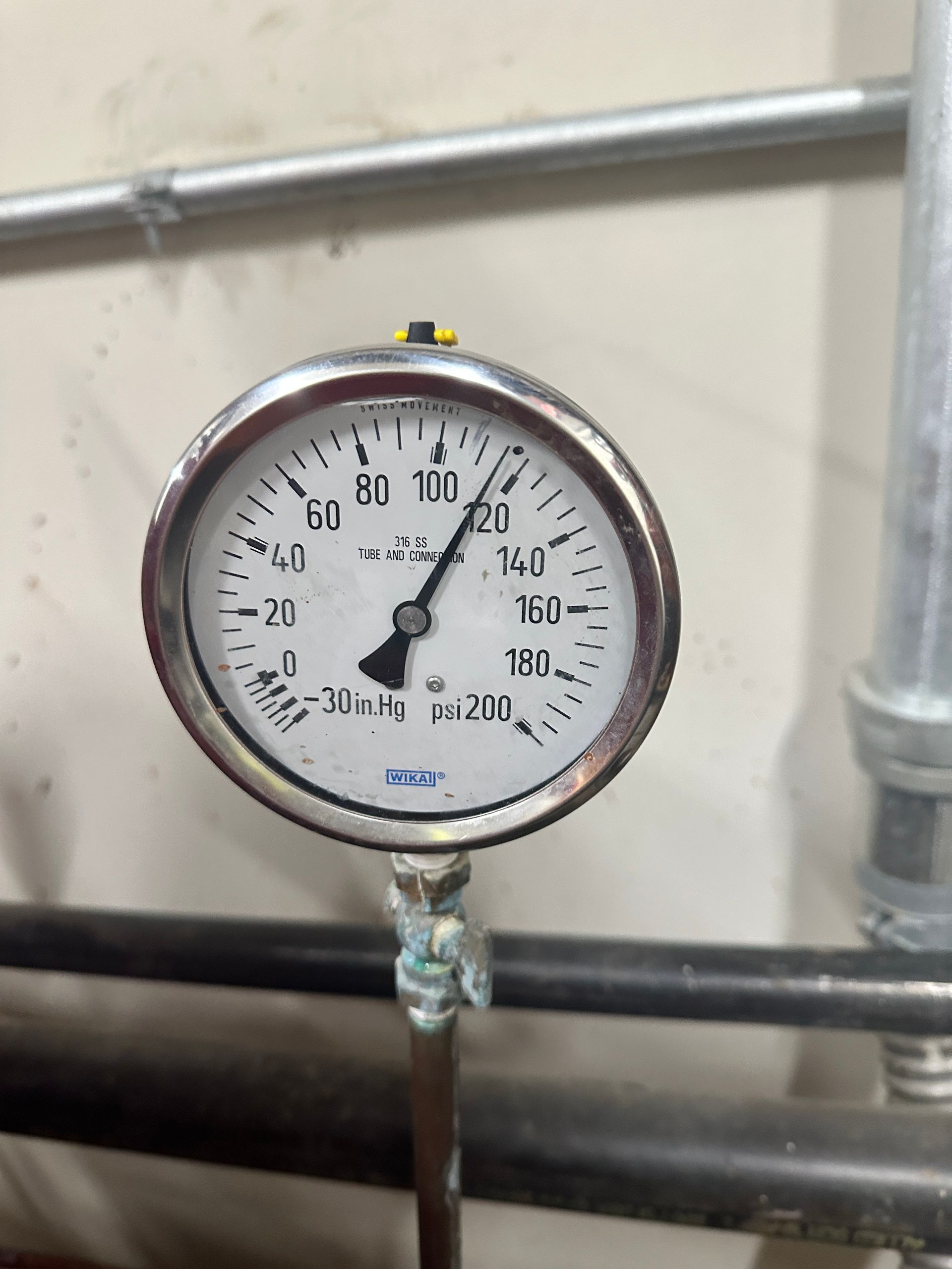 A close up of a pressure gauge on a pipe.