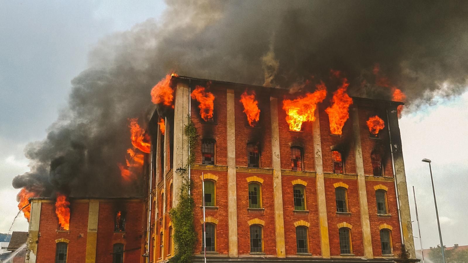 Building engulfed in flames and thick black smoke.