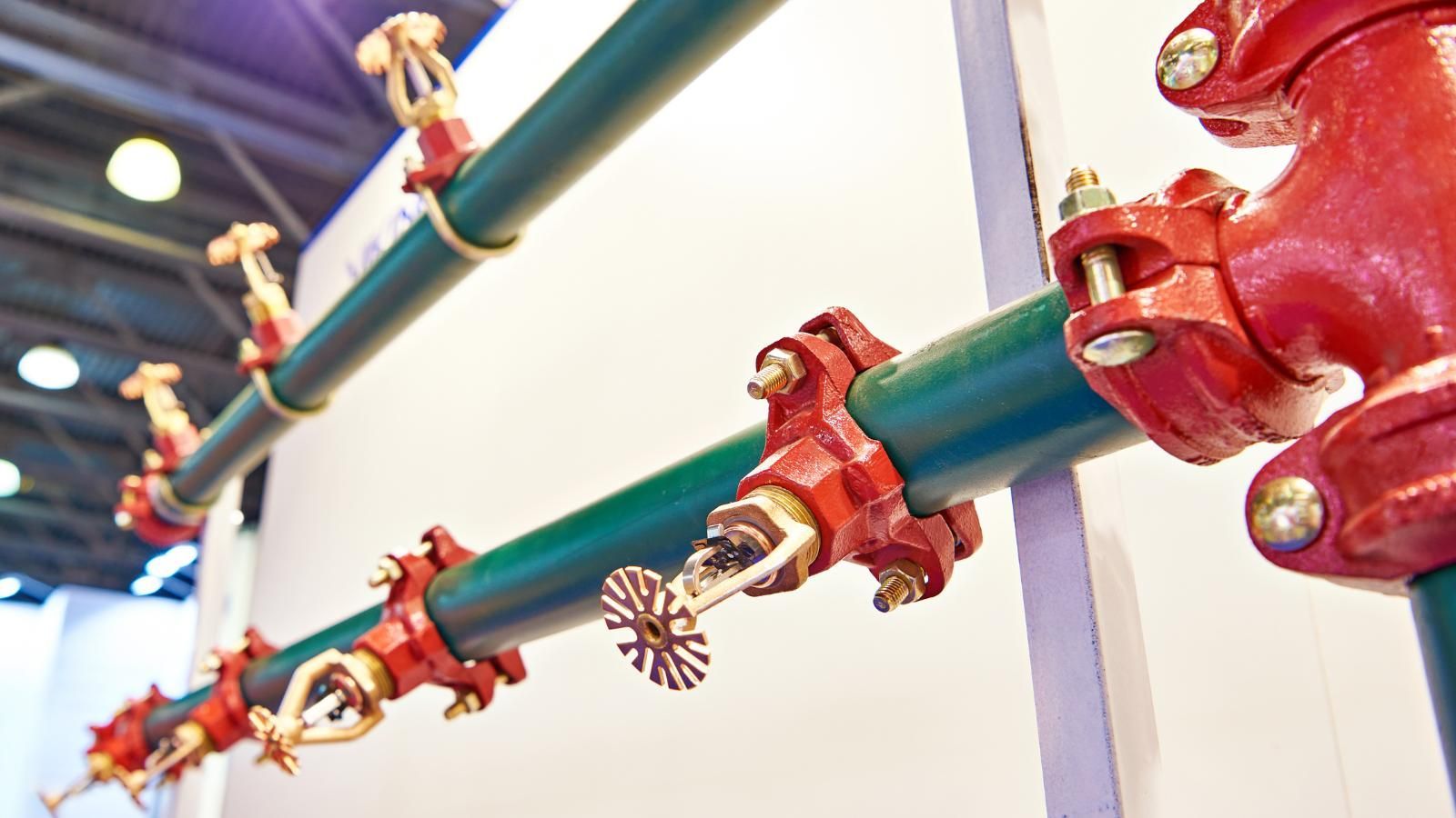 old sprinkler system A row of red and green pipes with sprinklers attached to them. The sprinkler heads are showing.