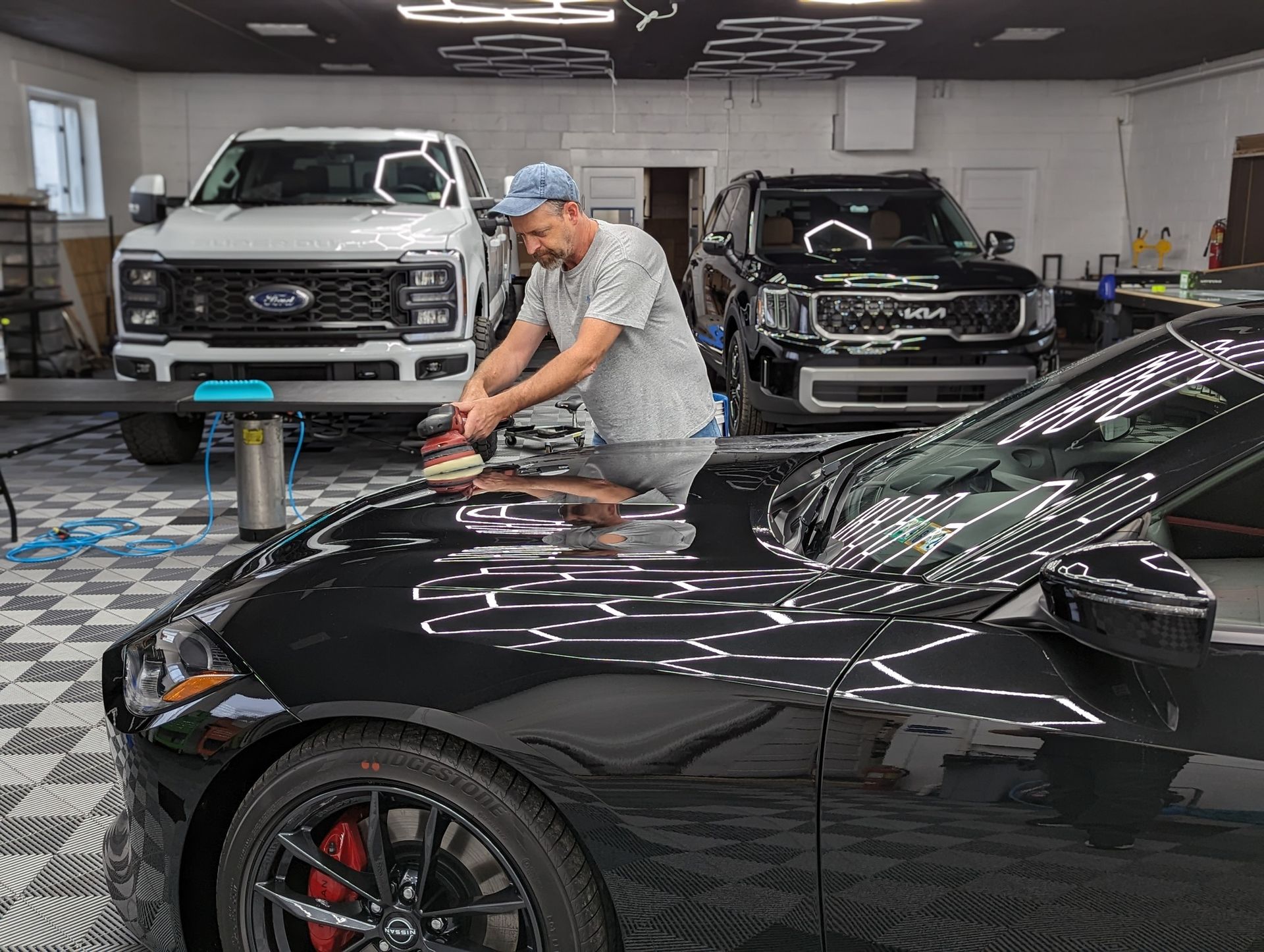 a man is polishing the hood of a black car in a garage .