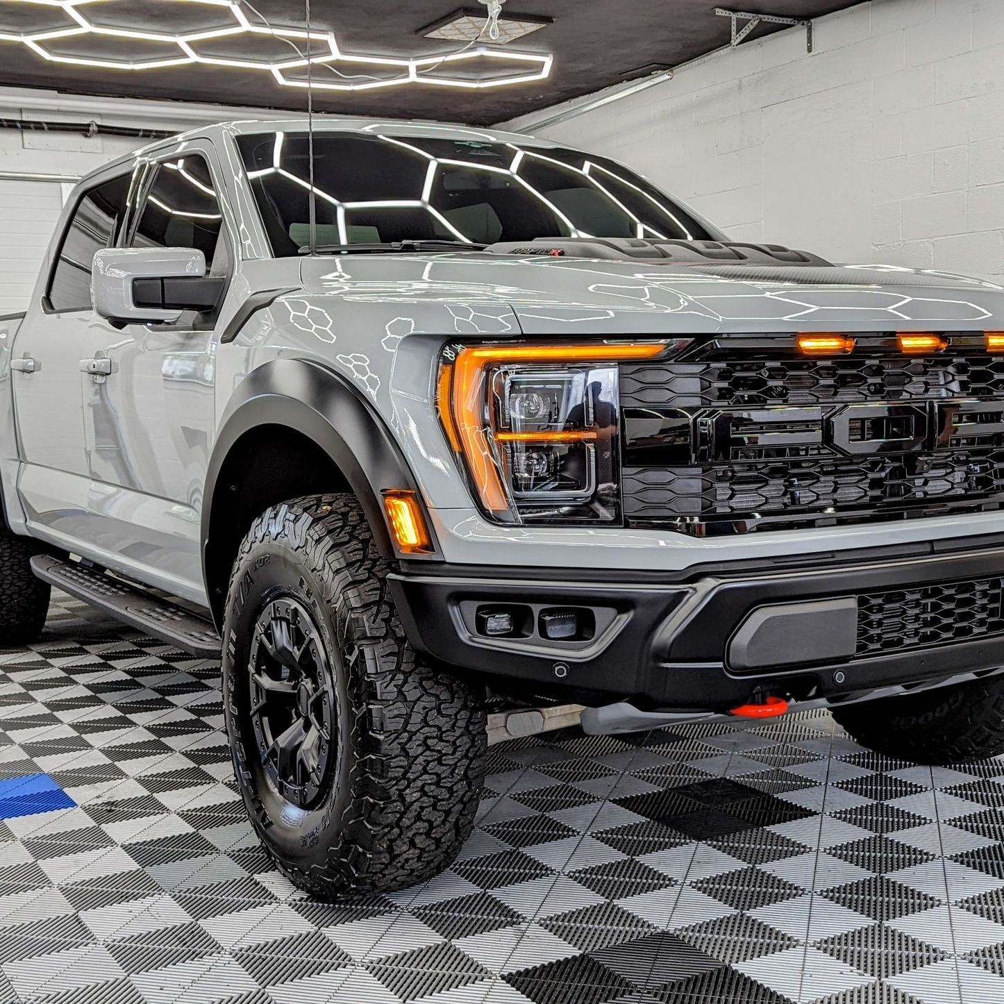 a gray ford raptor is parked in a garage on a checkered floor . Ceramic coating ppf johnstown pa