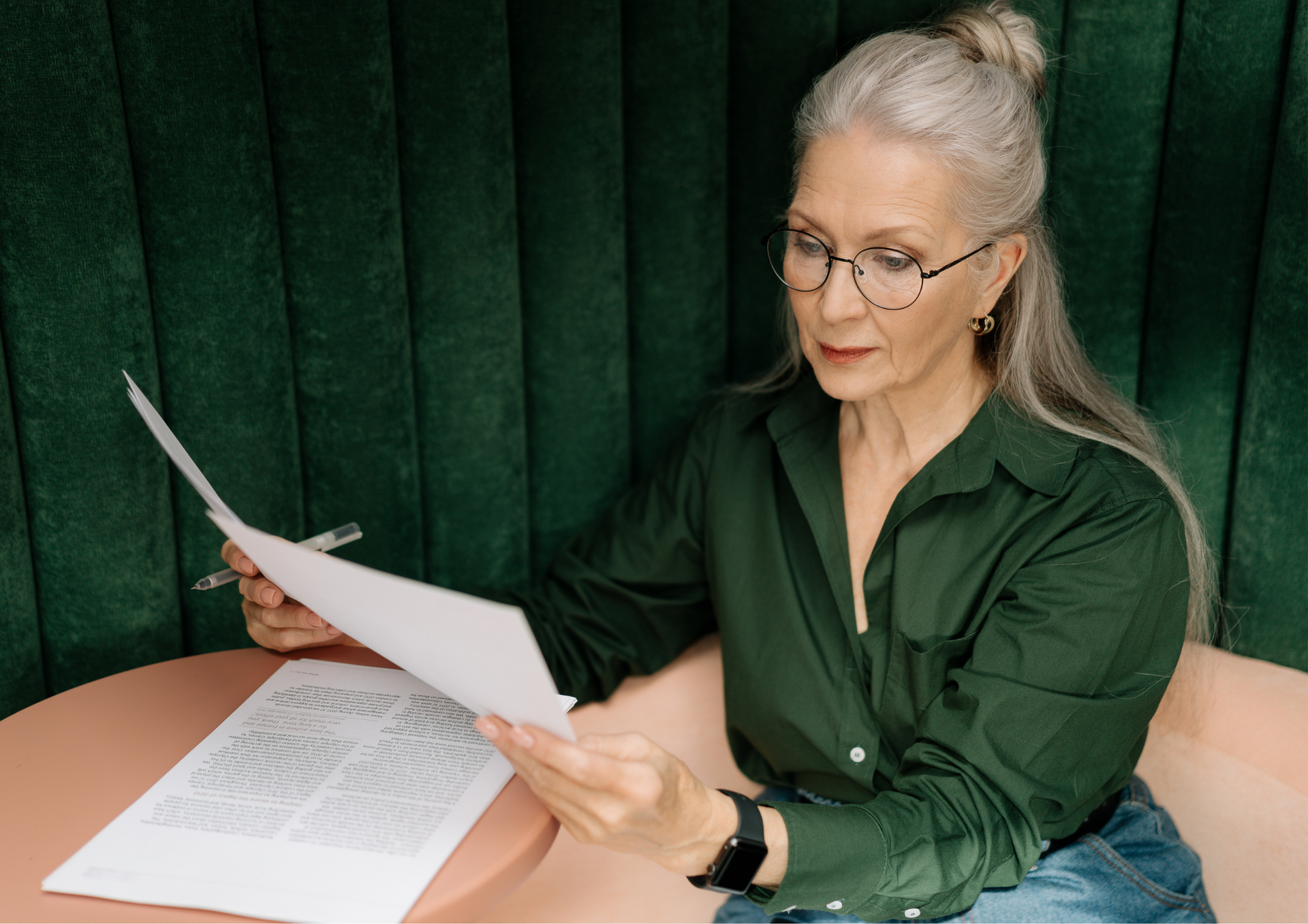 An older woman is sitting at a table reading a piece of paper.