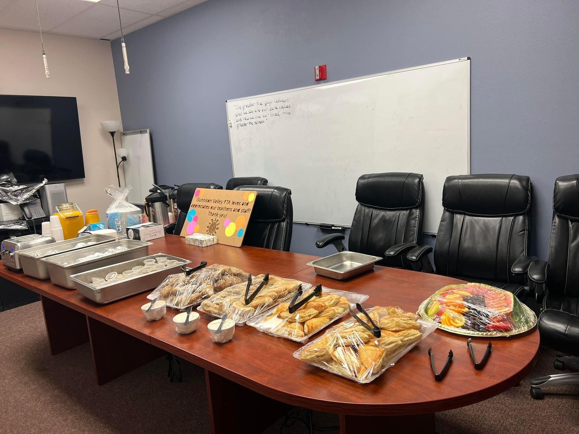A conference room with a long table filled with food and chairs.