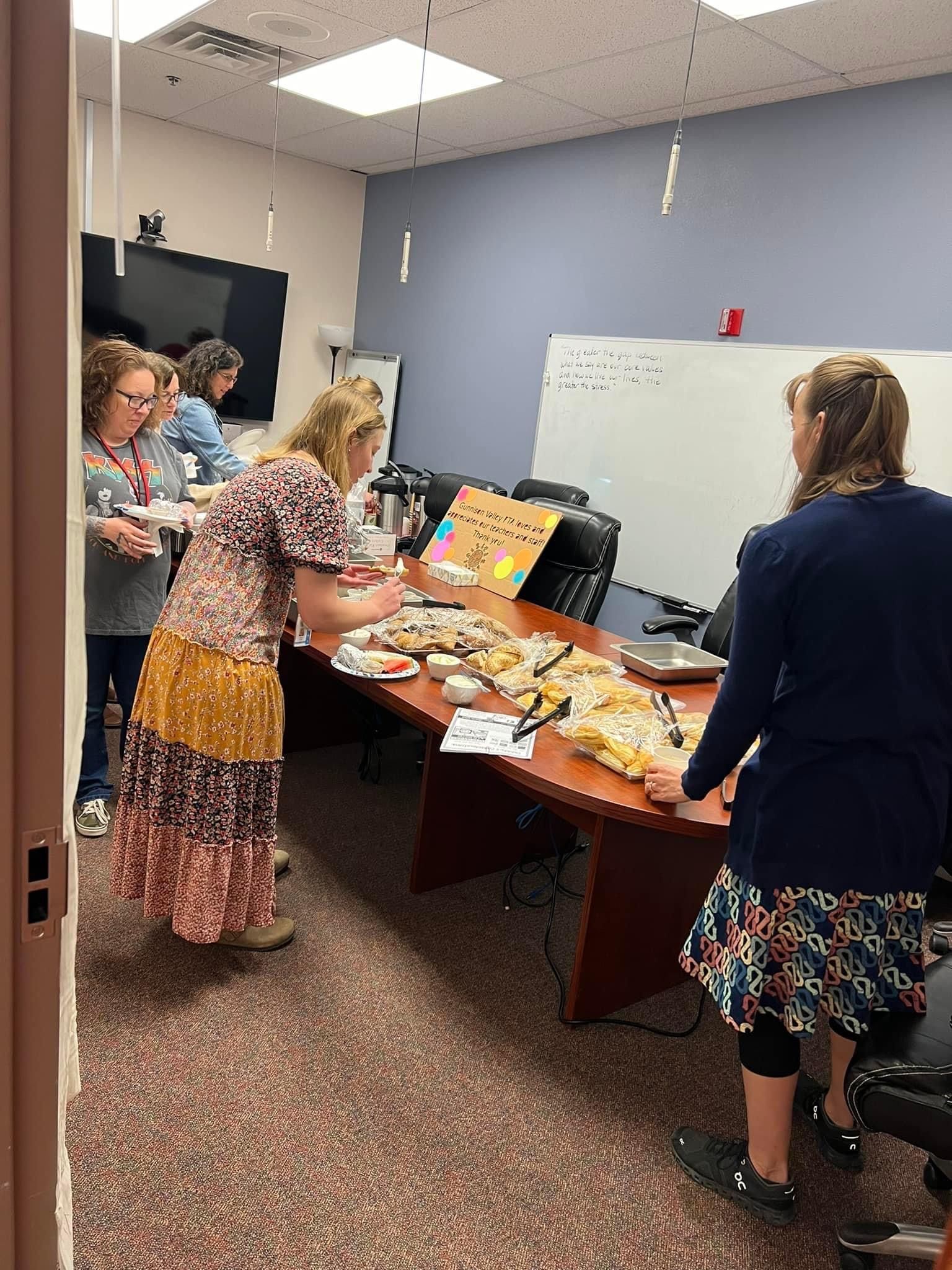 A group of women are standing around a table serving food.