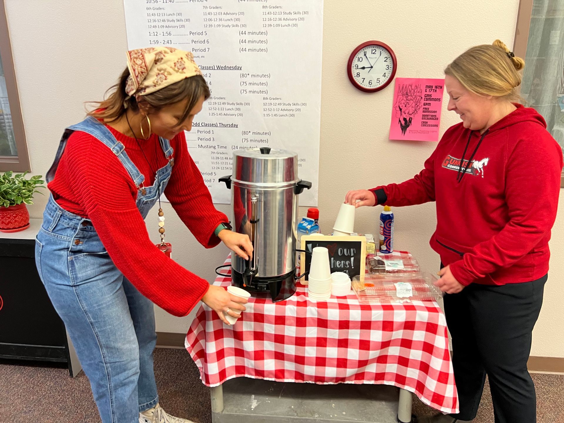 Two women are standing at a table with a coffee maker.