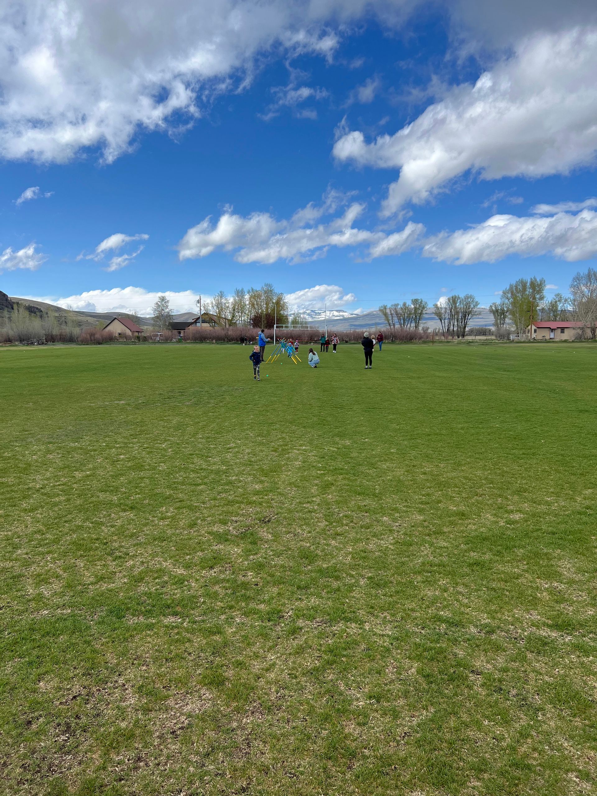 A group of people are running in a grassy field on a sunny day.
