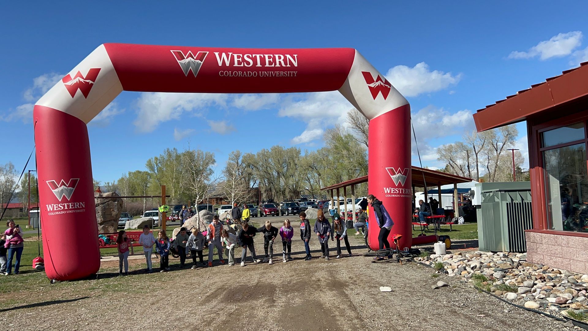 A group of people are standing under a red and white inflatable arch.