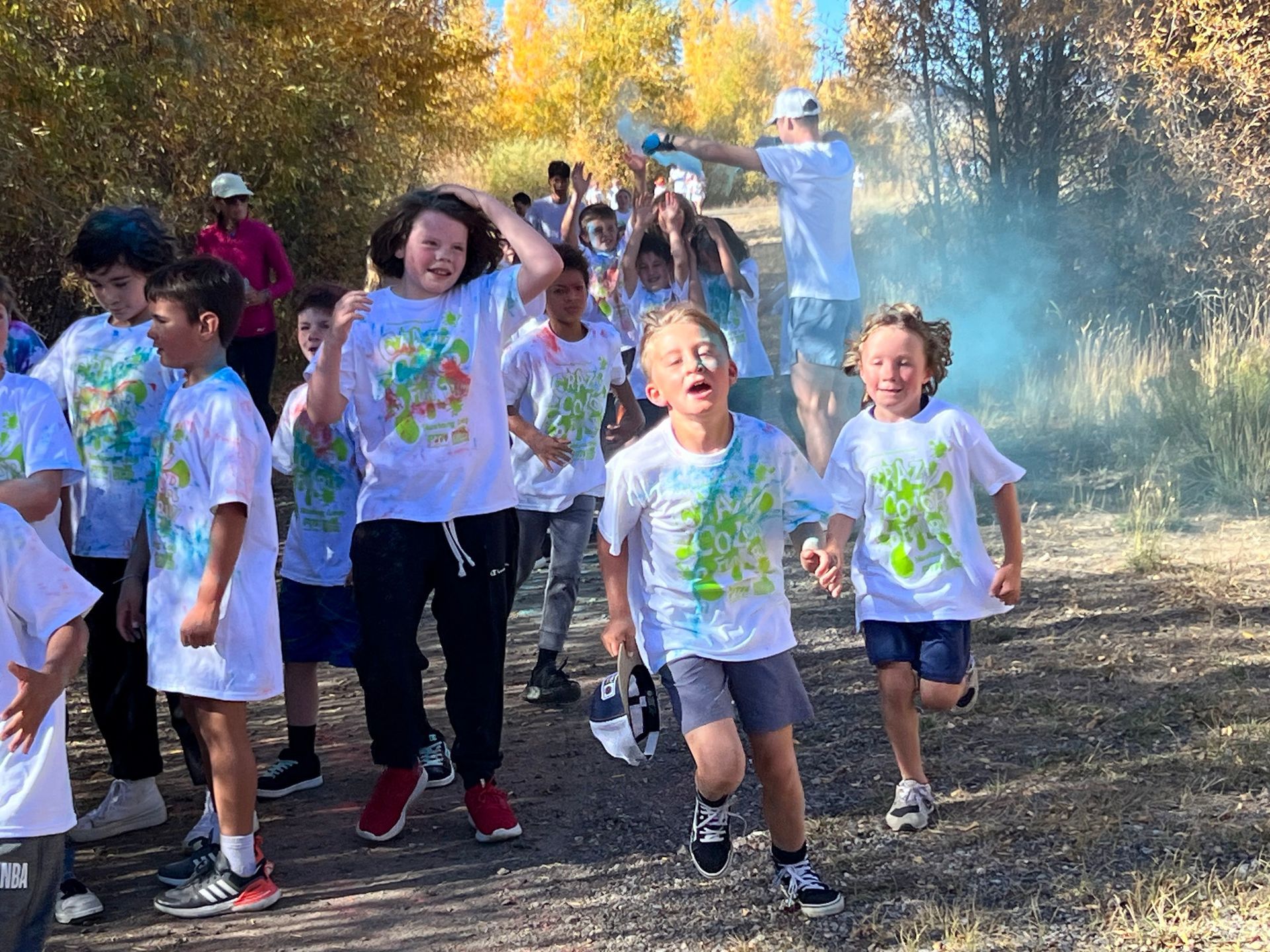 A young boy is covered in colored powder and wearing sunglasses.