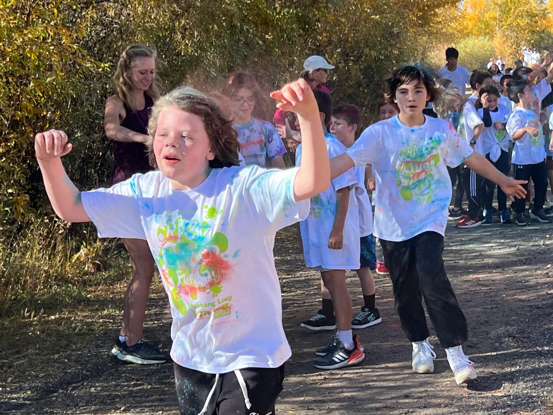 A group of children are dancing on a dirt road.