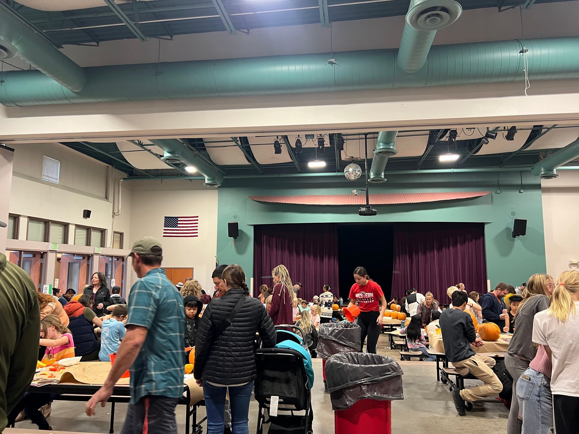 A group of people are standing around tables in a large room.