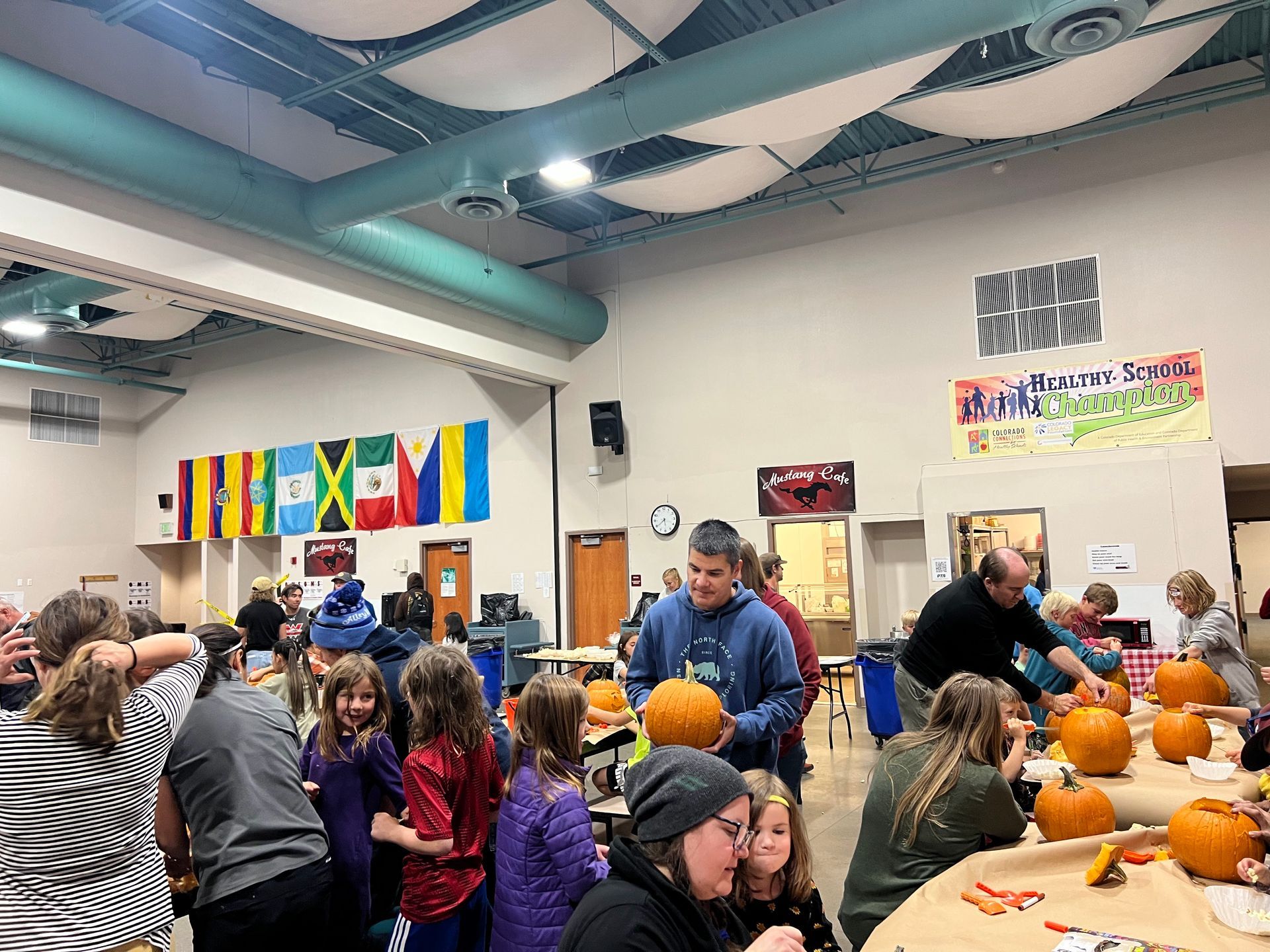 A group of people are carving pumpkins in a large room.