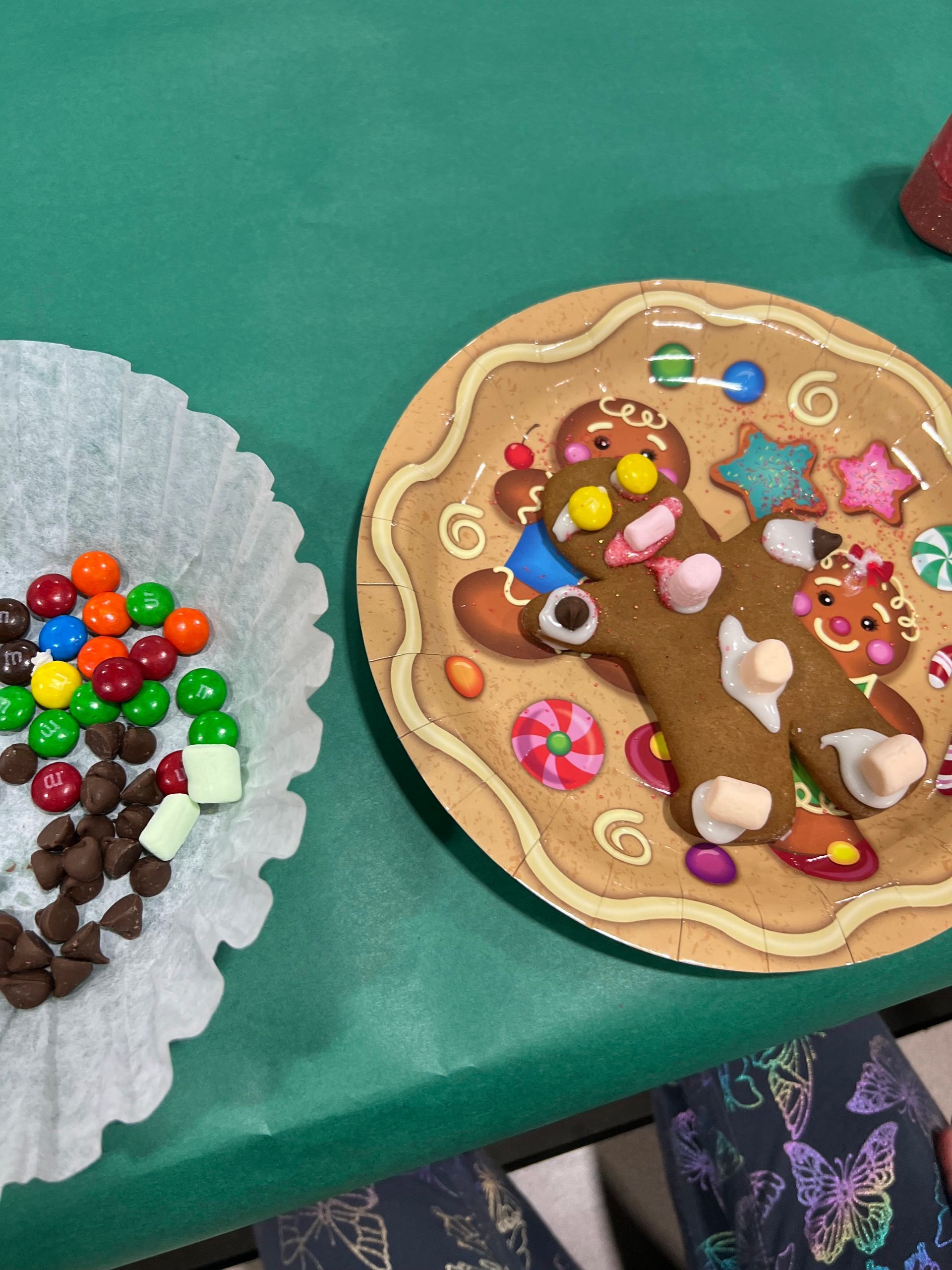 A gingerbread house decorated with santa claus and reindeer next to a christmas tree.