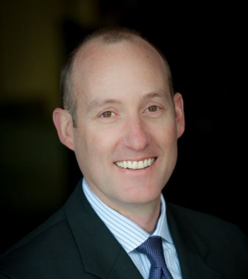 A man in a suit and tie is smiling for the camera