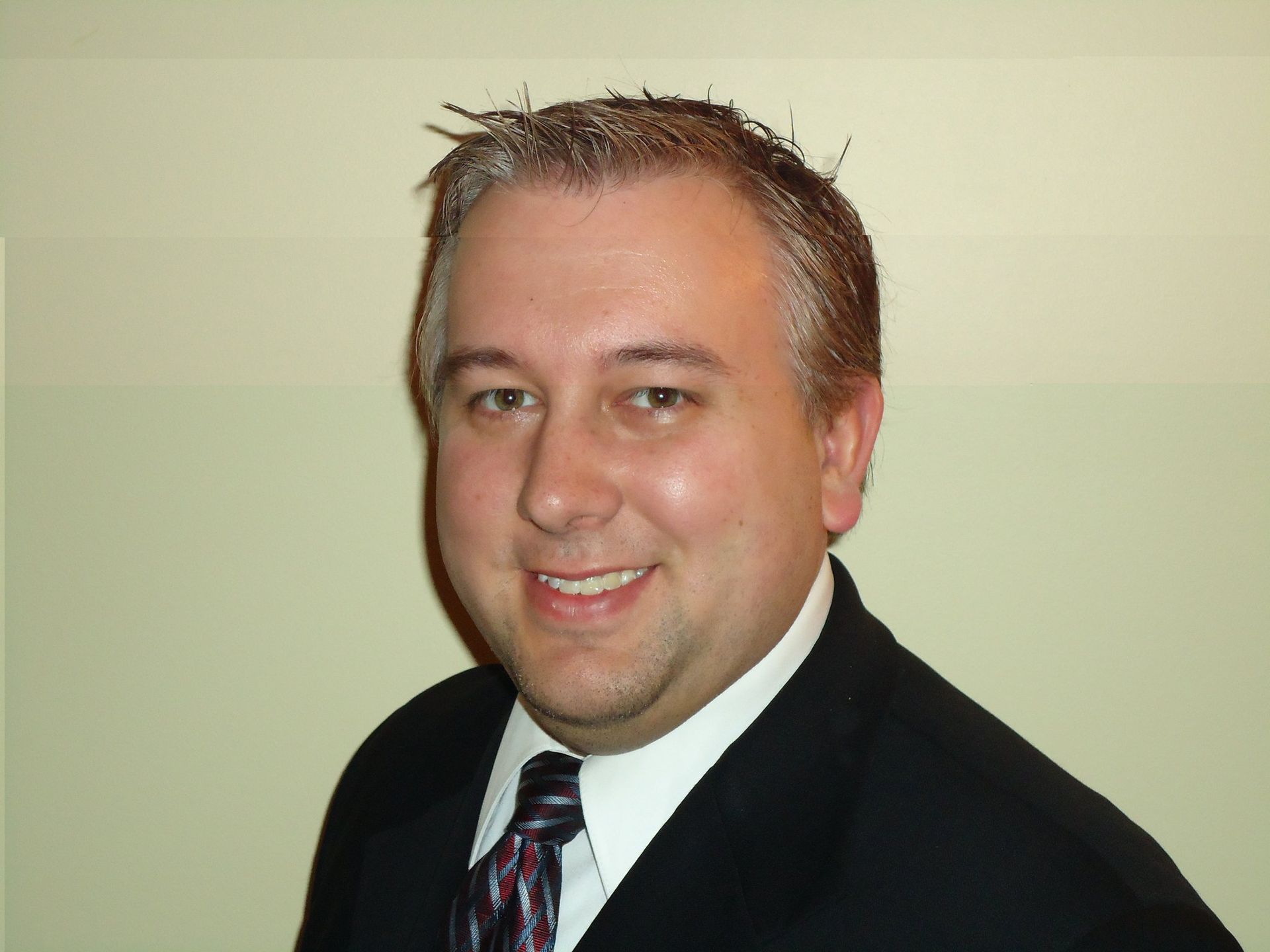 A man in a suit and tie is smiling for the camera