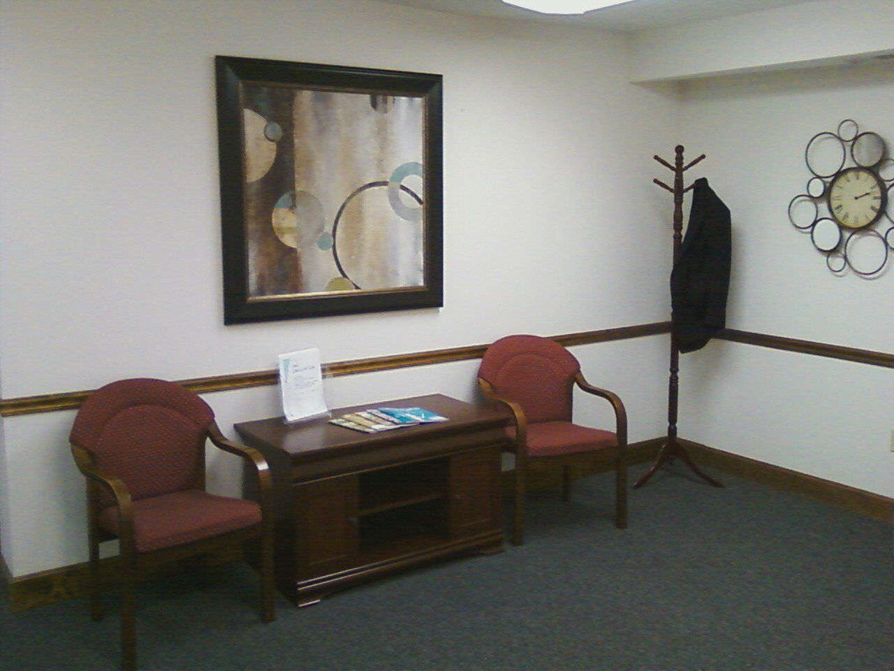 A waiting room with two chairs and a clock on the wall