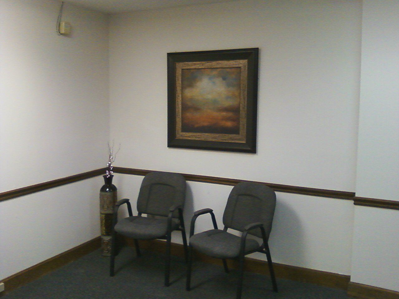 A waiting room with two chairs and a painting on the wall