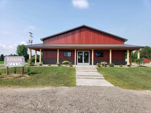 Red Brink building with red and brown siding, a sign, and a grassy lawn under a blue sky.