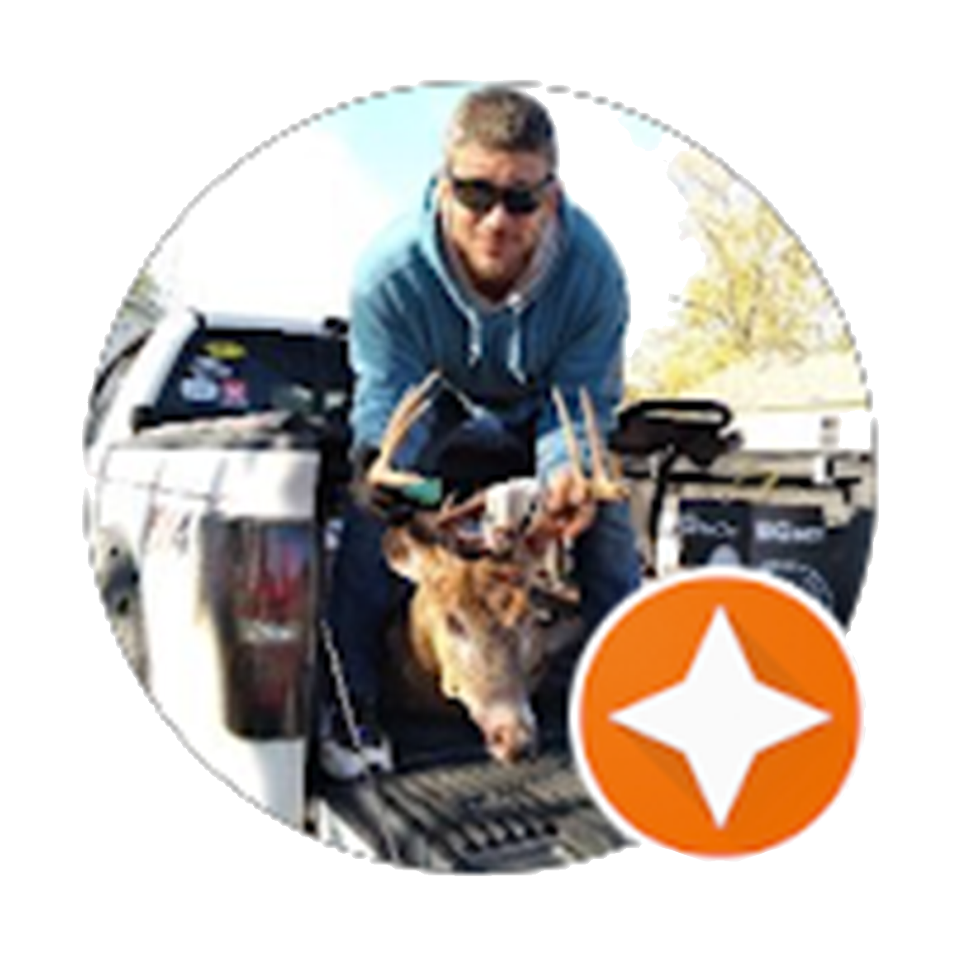 Man in blue hoodie, sunglasses, sits in truck bed with deer head, orange star logo in corner.