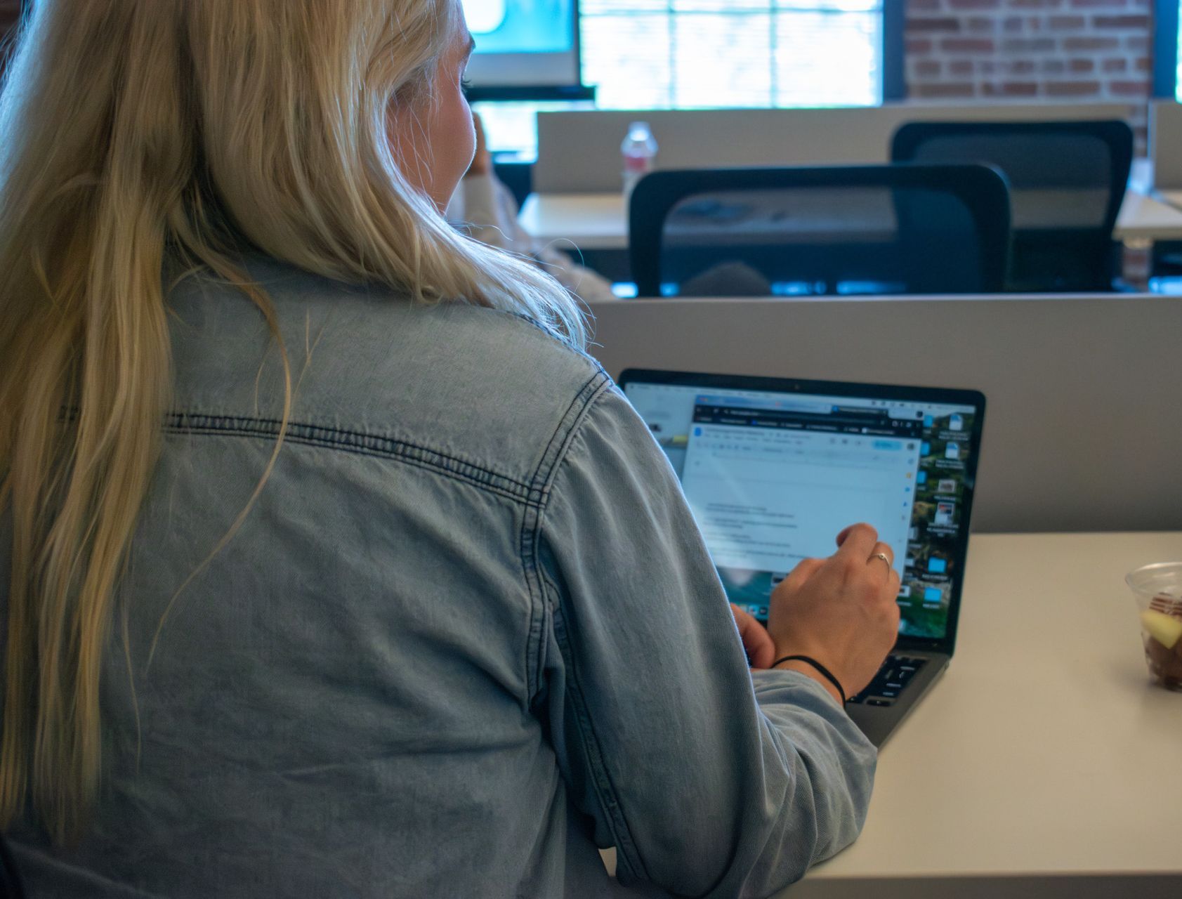 A woman is sitting at a desk using a laptop computer.