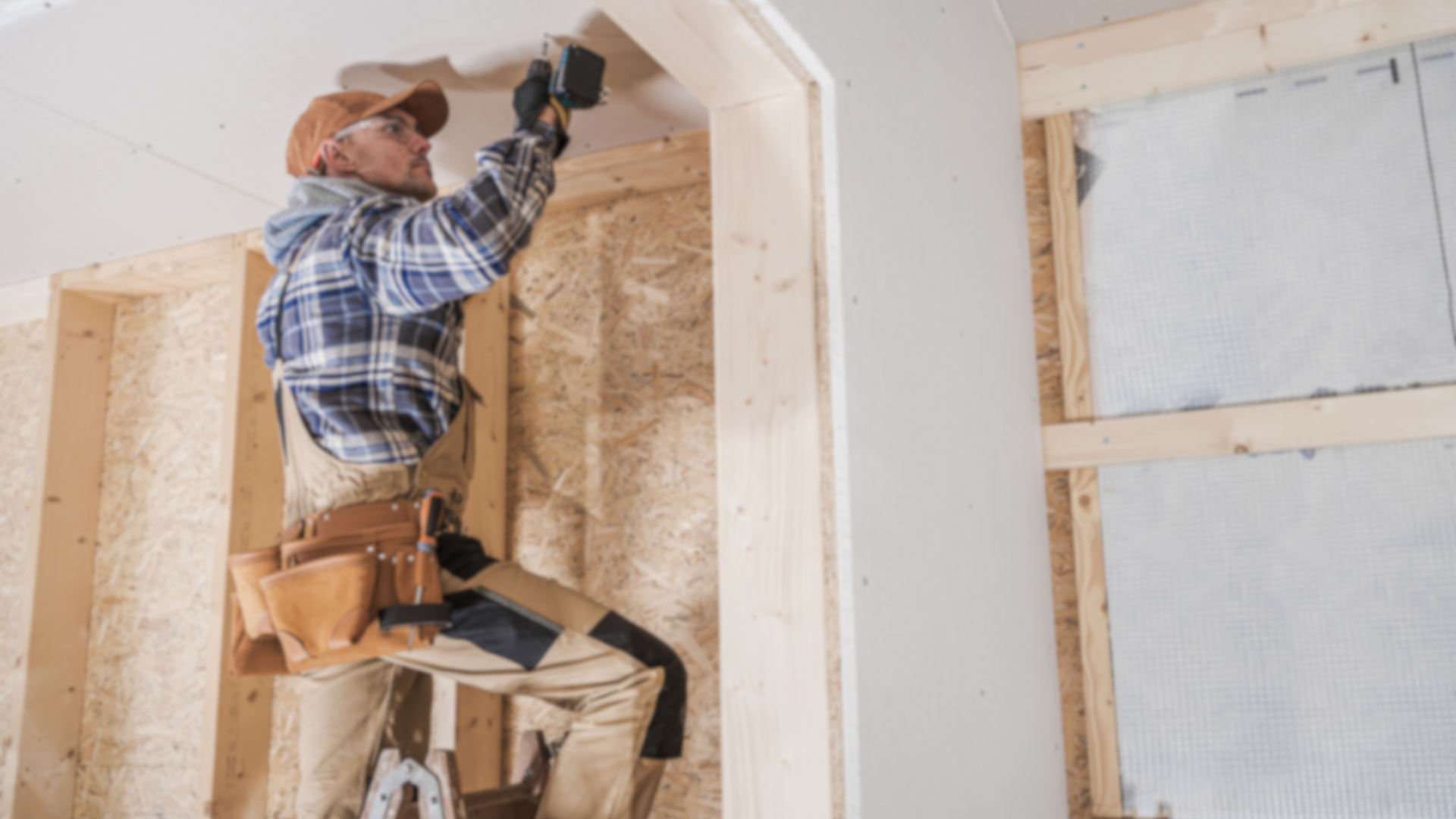 A man is working on a wooden wall in a room.