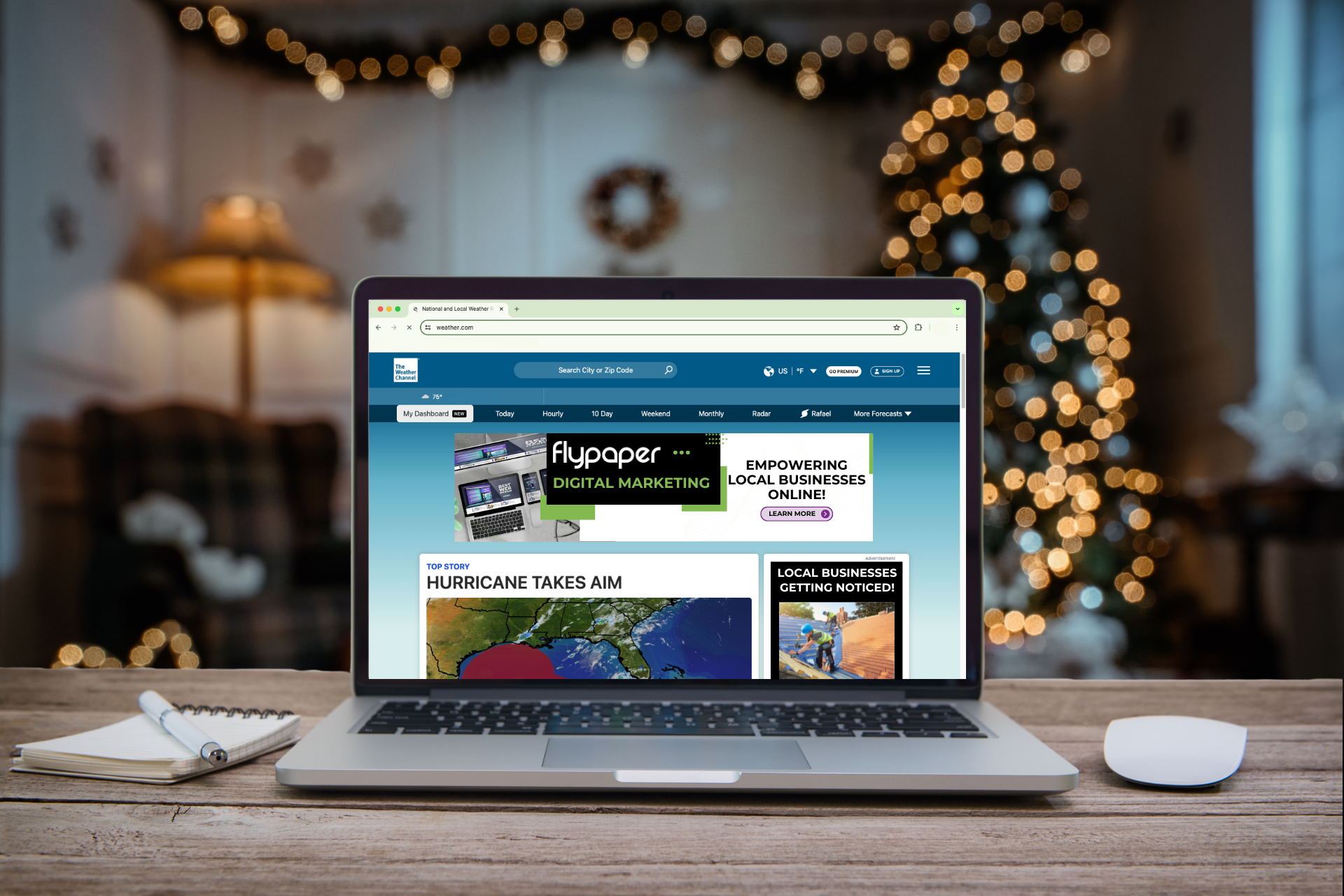 A laptop is sitting on a wooden desk in front of a christmas tree.