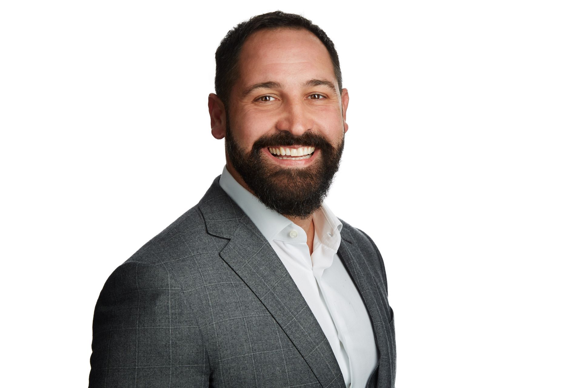 A man with a beard is wearing a suit and smiling.