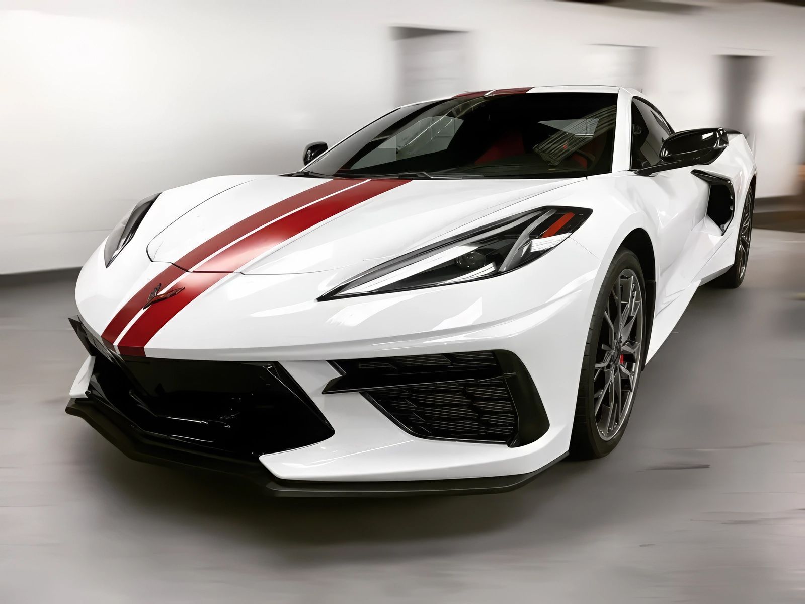 White Corvette sports car with red racing stripes, indoors.
