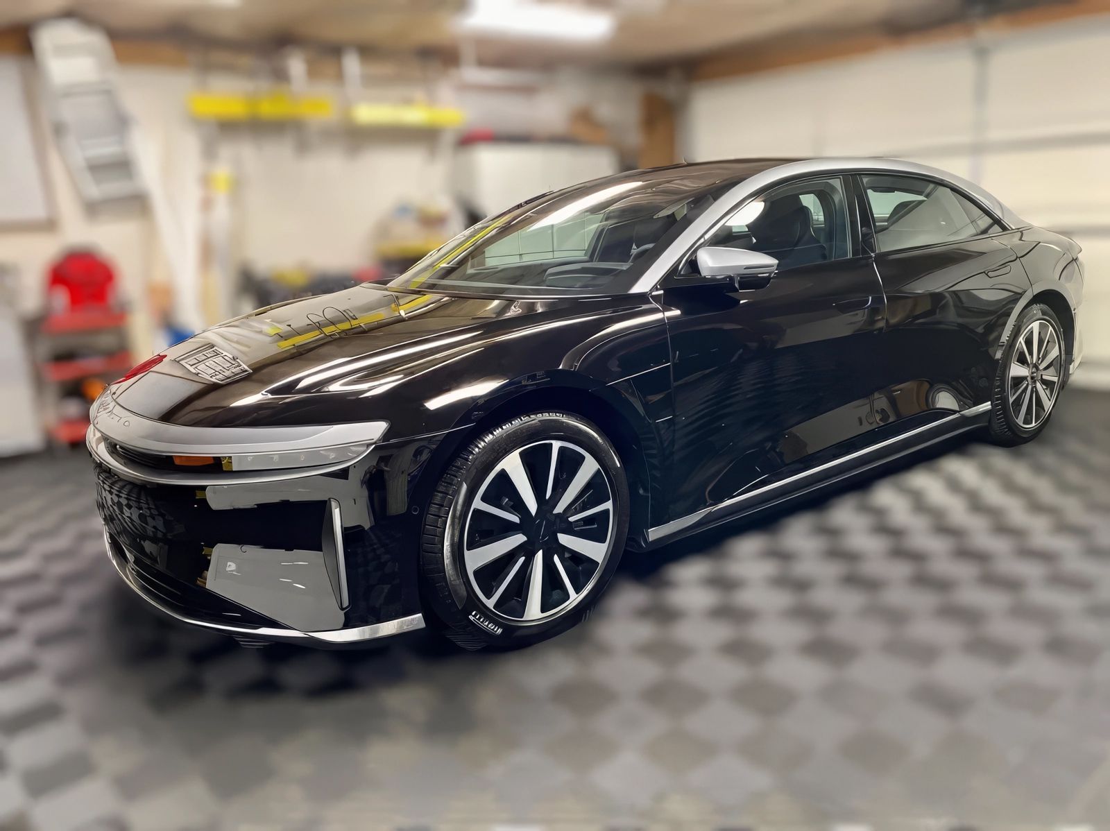 Black Lucid Air sedan parked in a garage, showcasing sleek design and silver accents.
