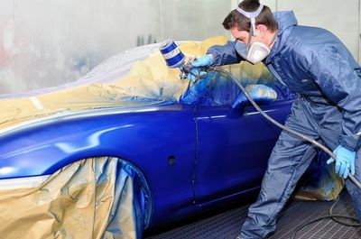 Auto Body Paint technician applying paint in shop in Buffalo, NY