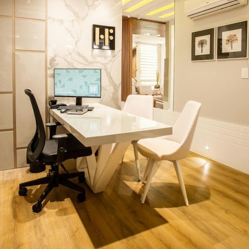 A desk with a computer and chairs in a room