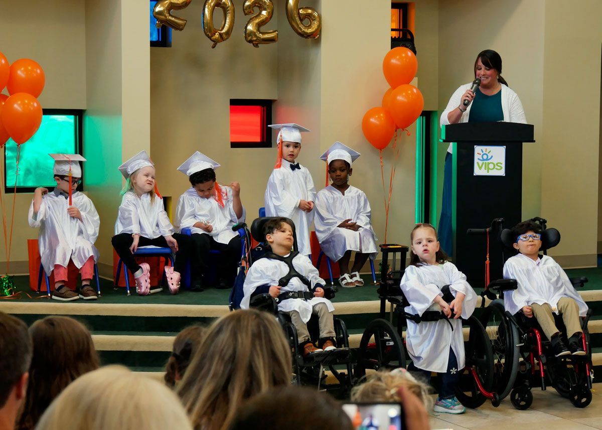 Miss Staci hands out diplomas to the Red Room graduates on the stage in Kids Town.