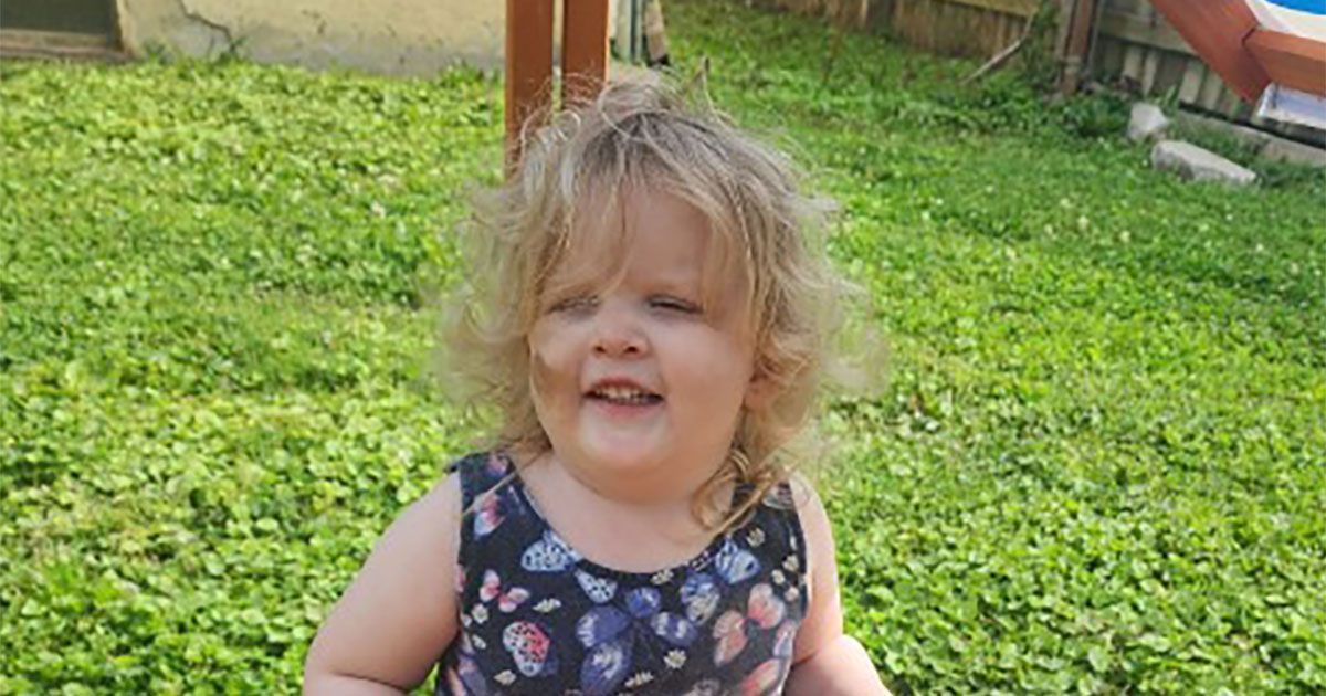 Roxanne smiles for the camera while sitting on the side of a sandbox.