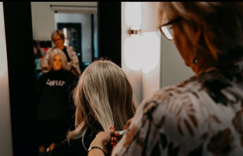 A woman is getting her hair cut by a hairdresser in a salon.