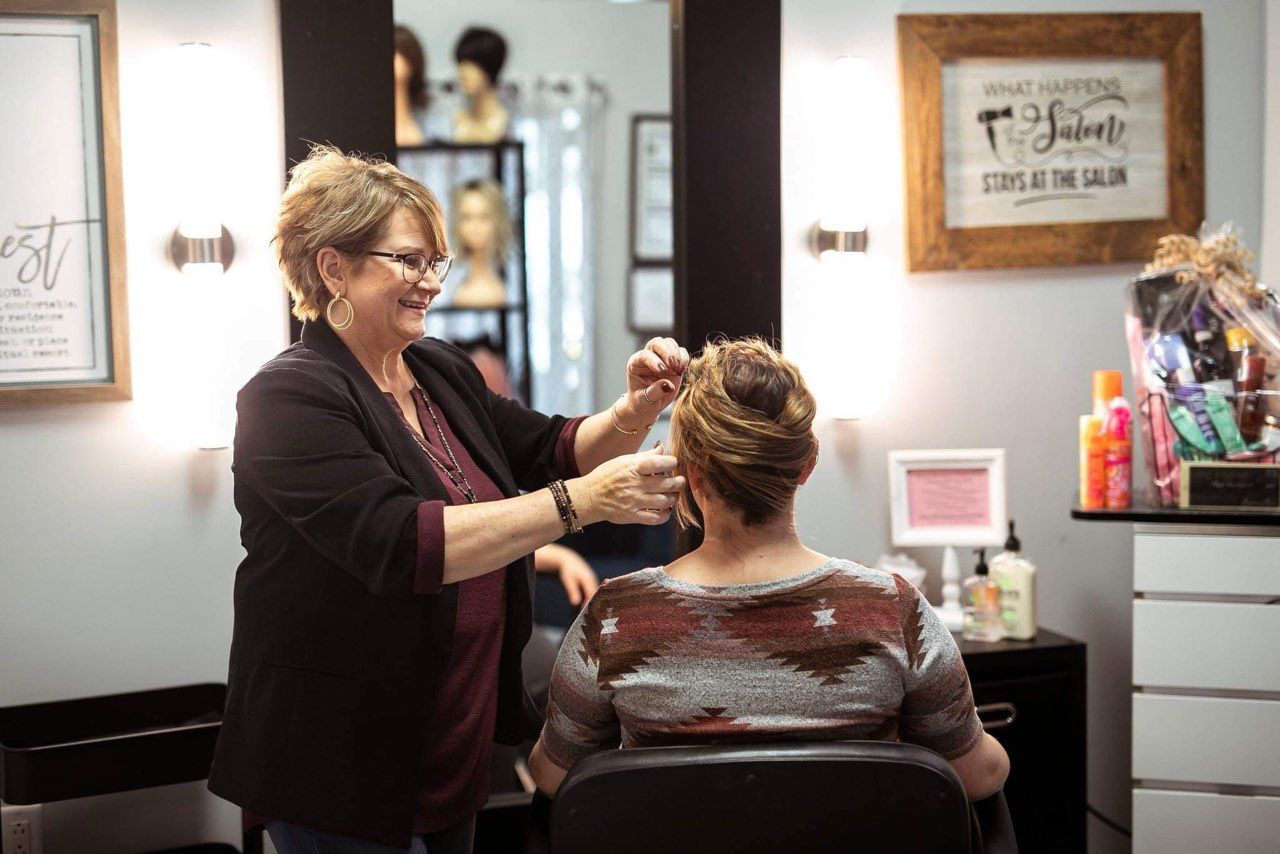A woman is getting her hair cut by a hairdresser in a salon.