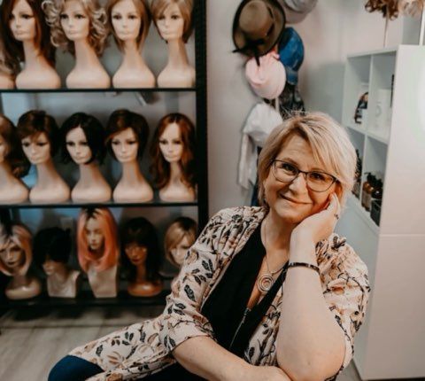A row of mannequins wearing wigs in a store.