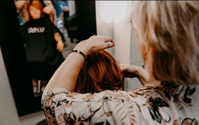 The back of a woman with red and purple hair.