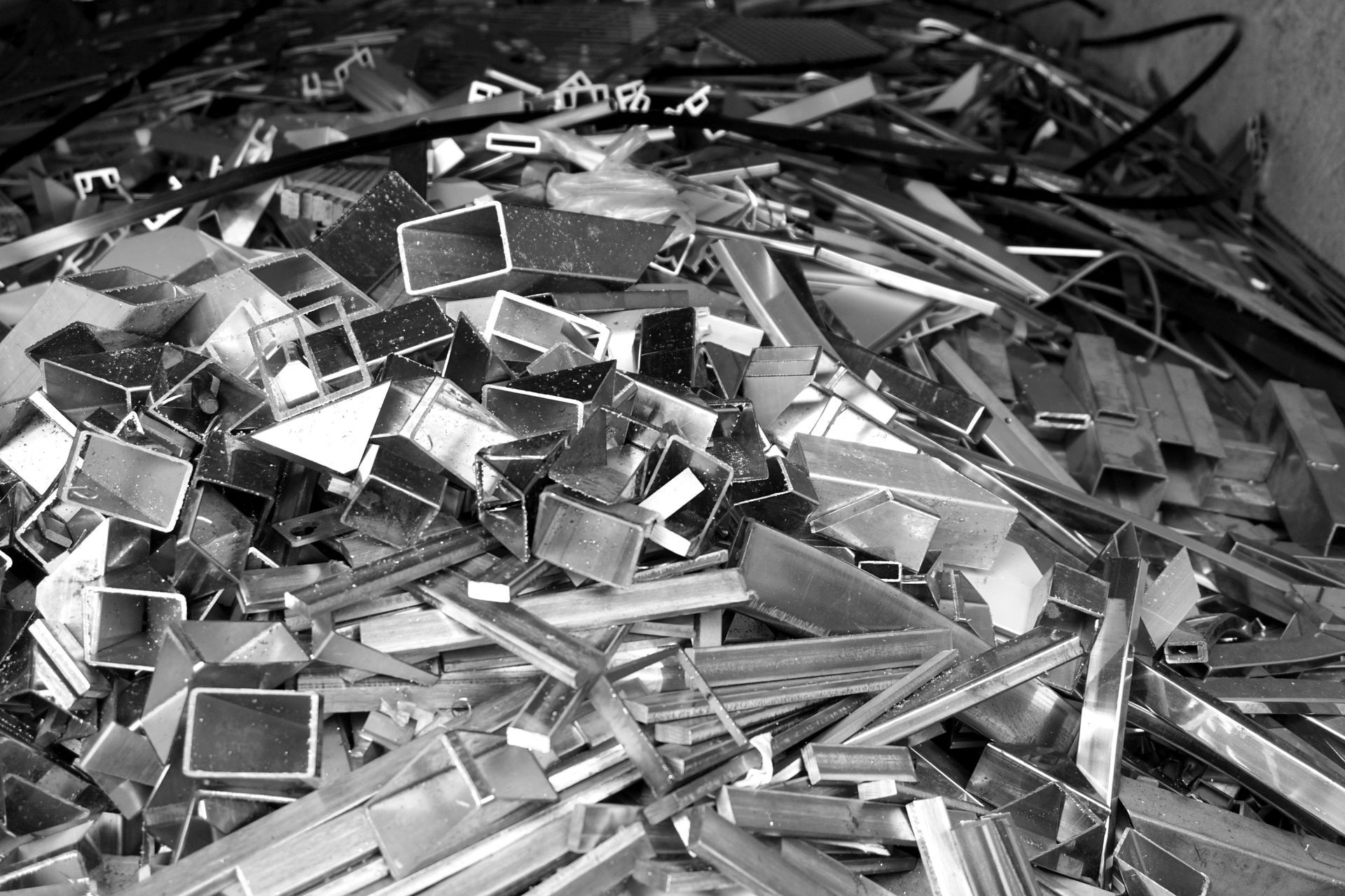 Pile of shiny, fragmented metal pieces, possibly scrap aluminum, in an industrial setting.