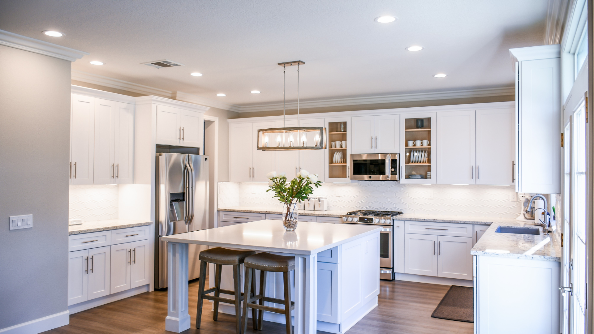 a kitchen with white cabinets , stainless steel appliances , and a large island .