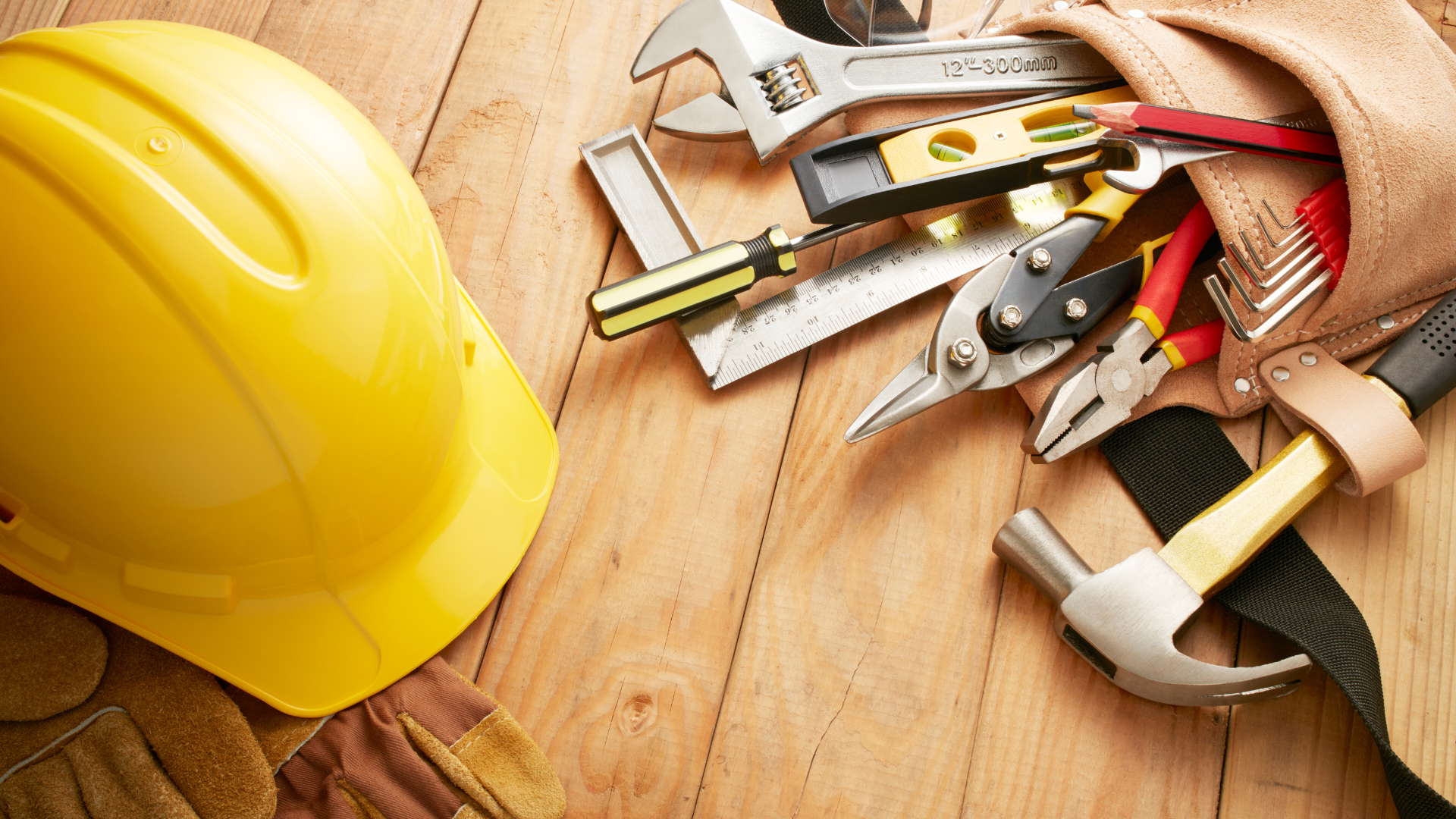 a hard hat is sitting on a wooden table next to a tool belt filled with tools .