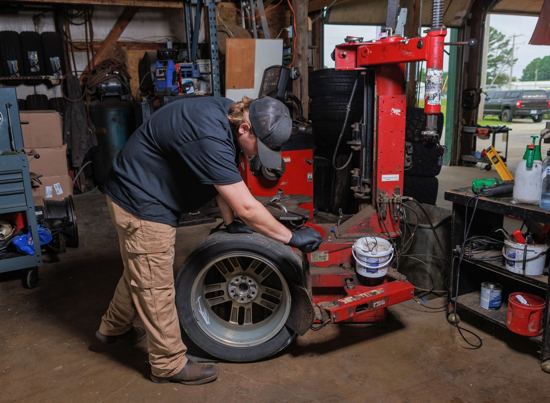 Mechanic working on a tire with a machine in a garage.
