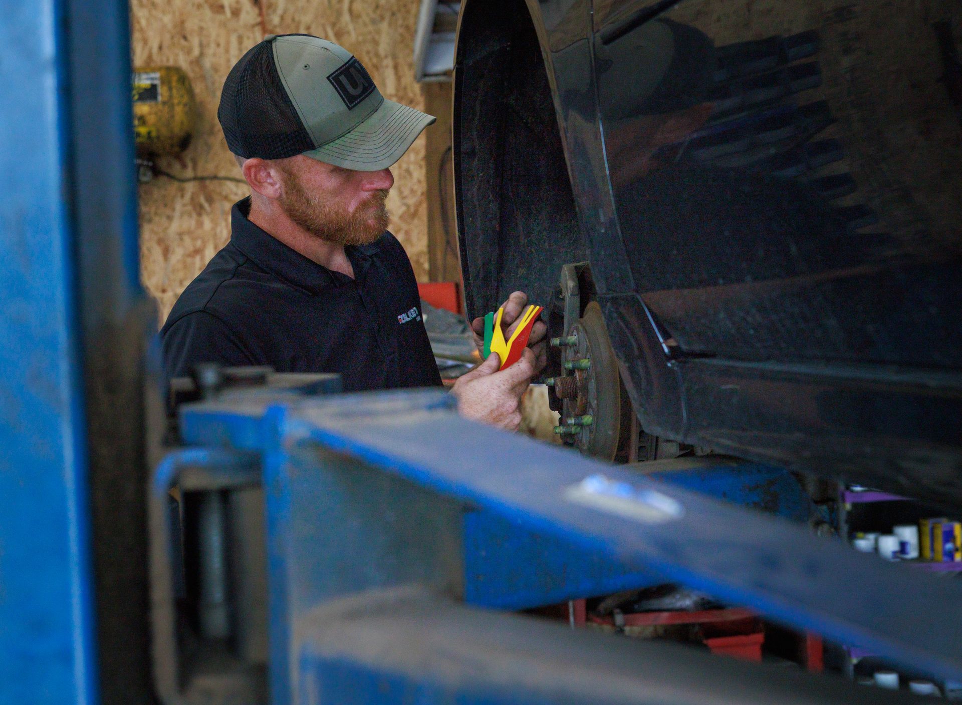 Mechanic working on a car, using tools, in a garage.