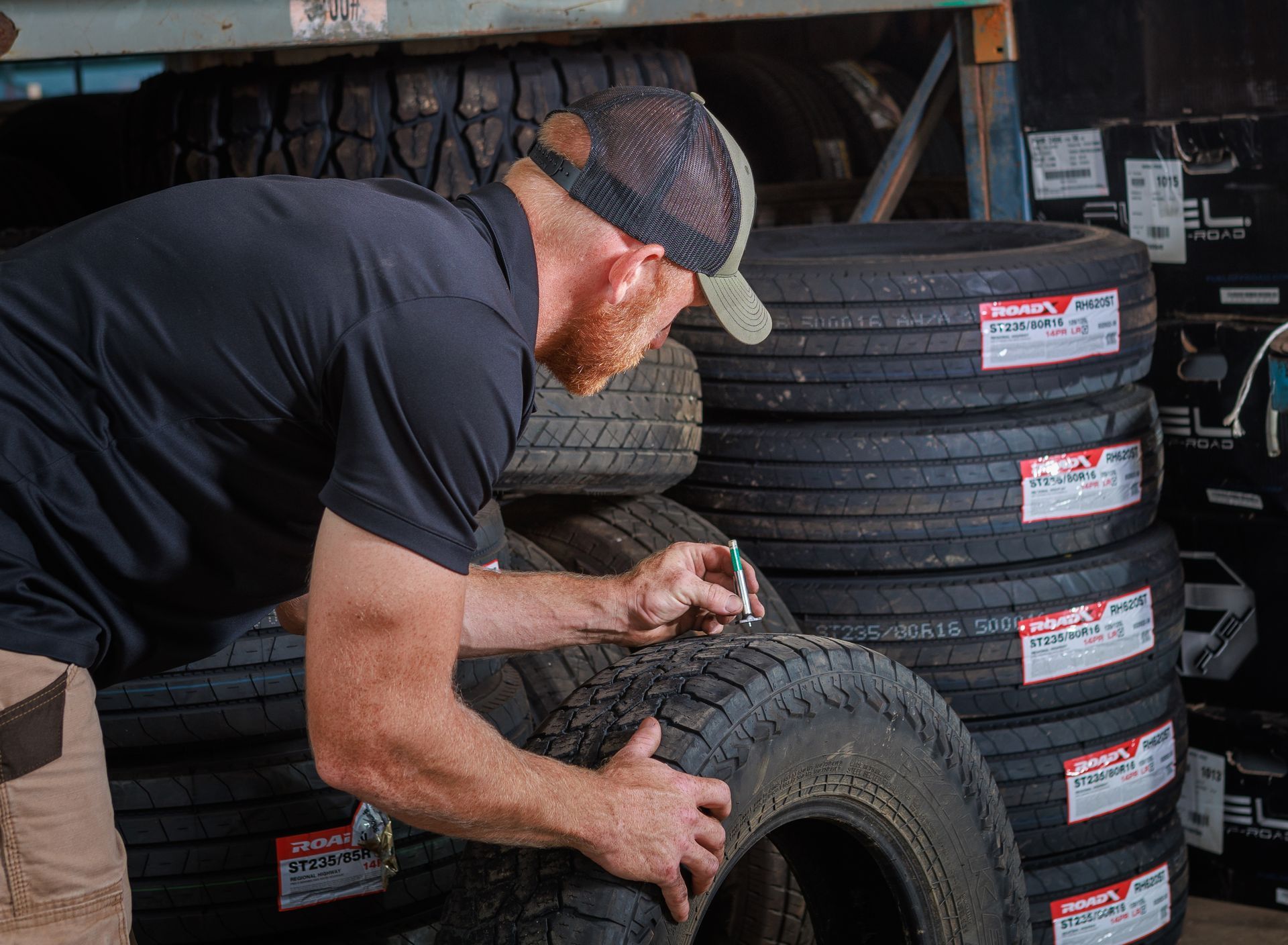 Man inspecting tires stacked on shelves in a warehouse.
