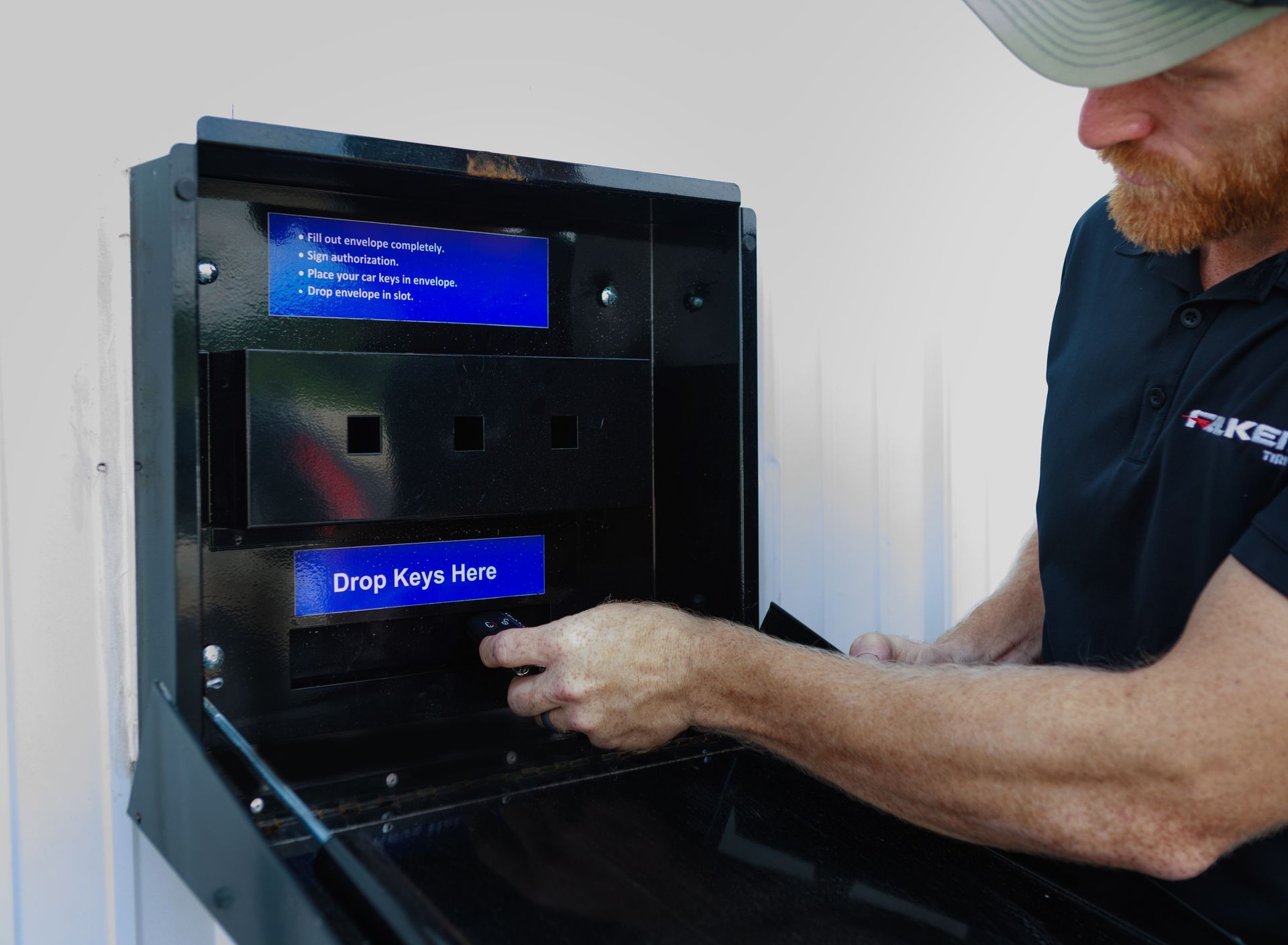 Man interacting with a black key drop box, opening the bottom door.
