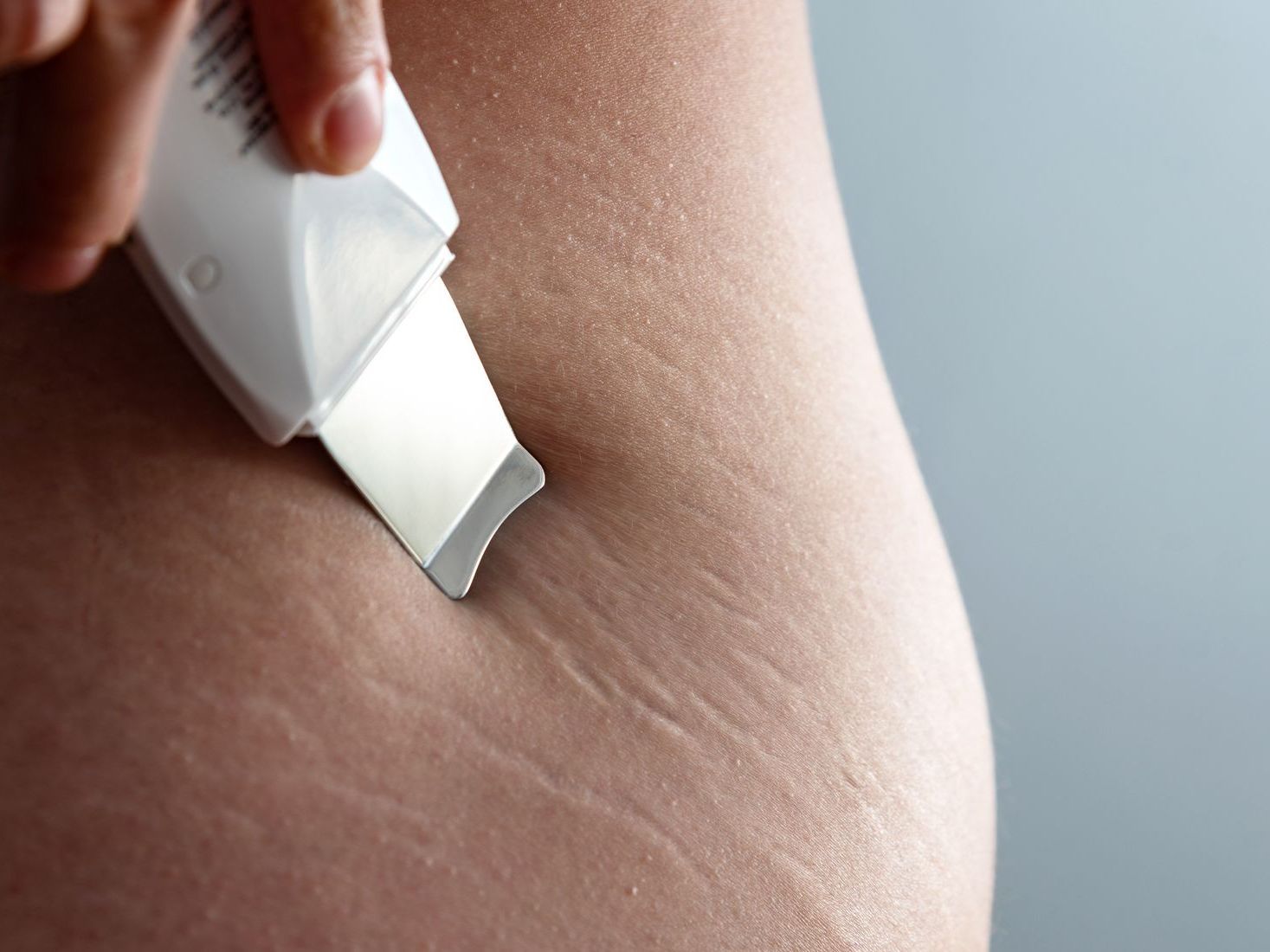 A close up of a person using a device on their skin