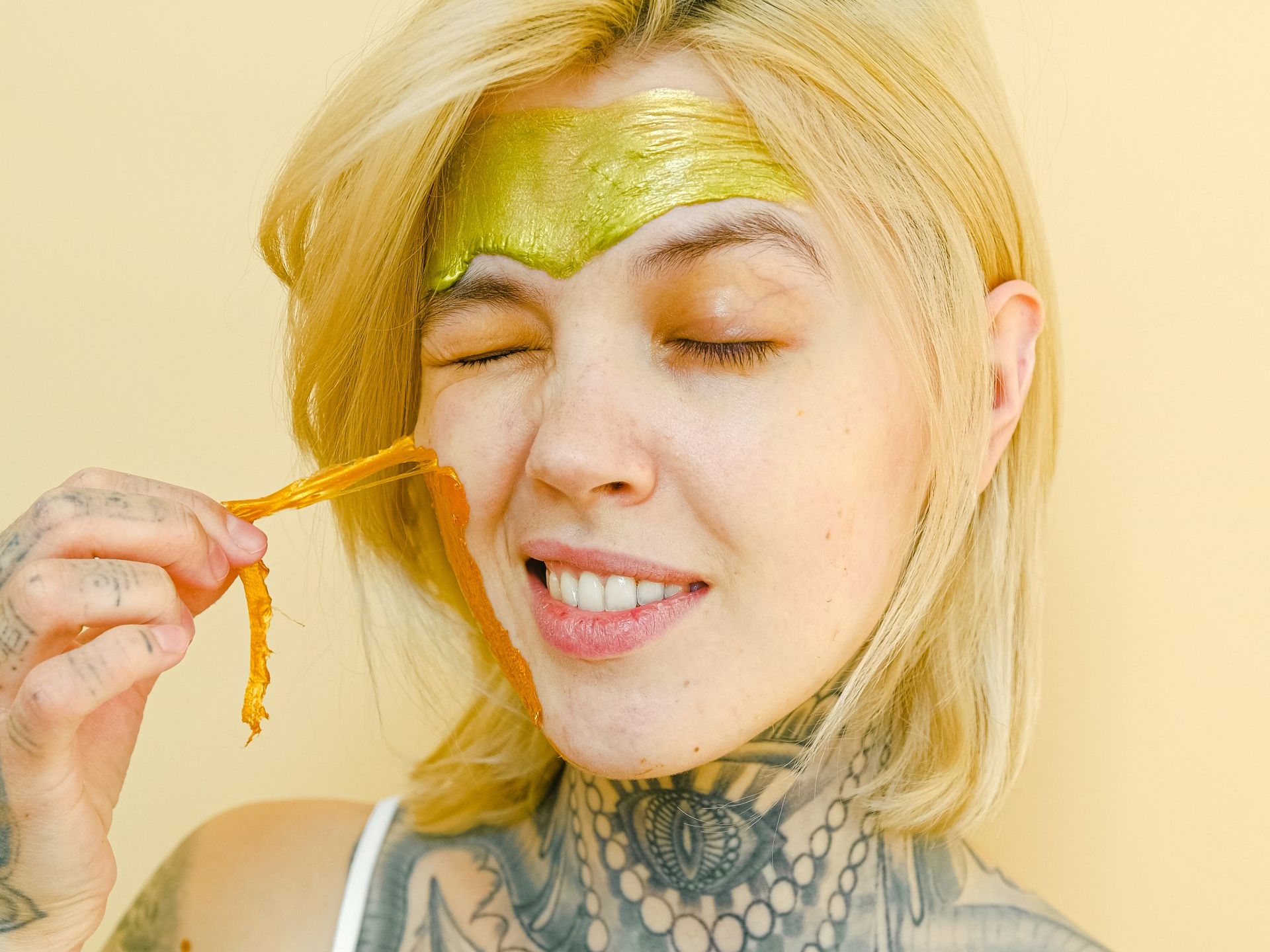 A woman is applying a gold mask to her face.